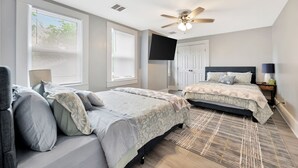 A bedroom with two beds, a ceiling fan, a TV, and a door. - Wichita home, by the river, spacious 9 beds-game room with pool table, 1gb Wi-Fi (Wichita)