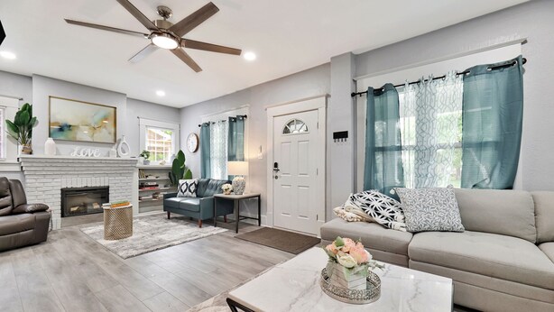 A spacious living room with a fireplace, a ceiling fan, and a sofa. - Wichita home, by the river, spacious 9 beds-game room with pool table, 1gb Wi-Fi (Wichita)