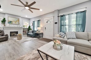 A spacious living room with a fireplace, a ceiling fan, and a sofa. - Wichita home, by the river, spacious 9 beds-game room with pool table, 1gb Wi-Fi (Wichita)