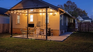 A house with a covered patio area, outdoor seating, and string lights.