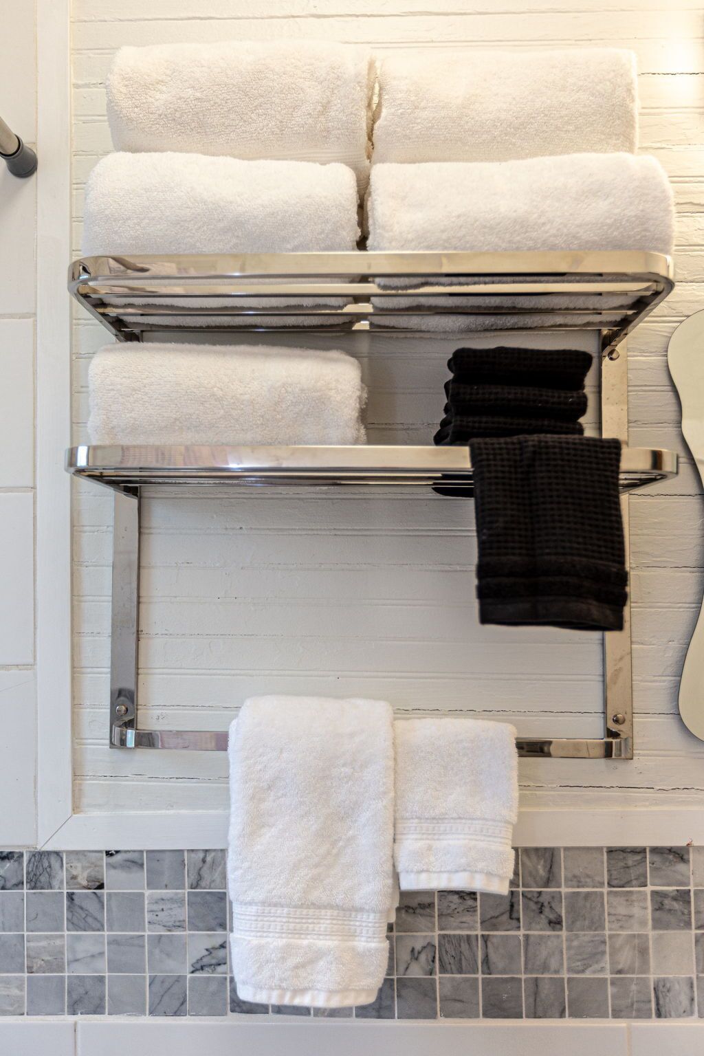 Ein Badezimmer mit Handtuchhalter und mehreren weißen Handtüchern sowie einem schwarzen Handtuch.