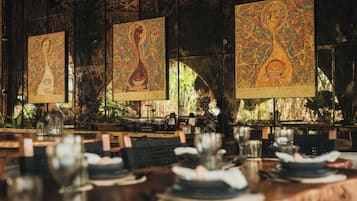 Un restaurante con detalles de mosaicos en las paredes, mesas y sillas de madera.