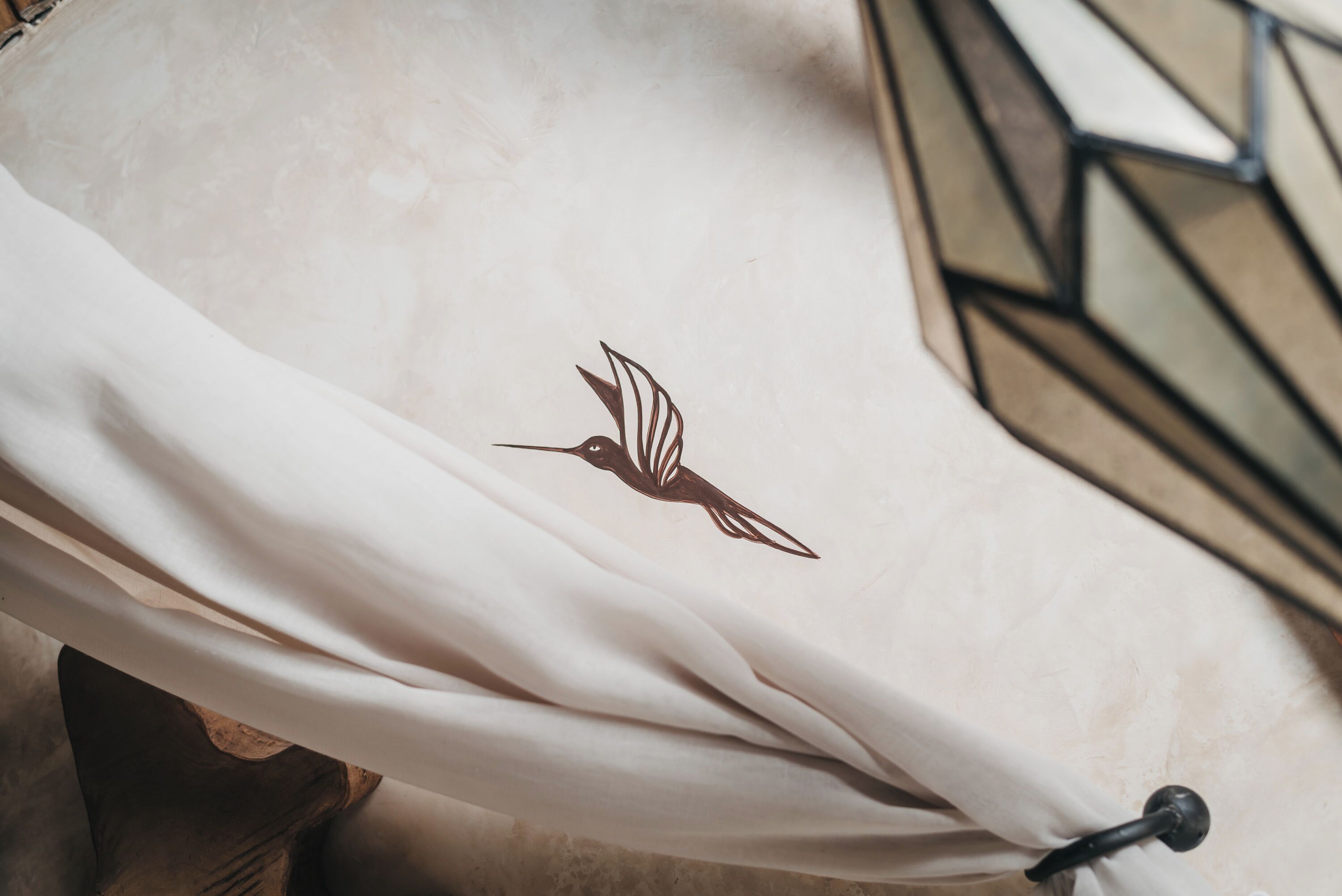 Tejido blanco con un diseño de pájaro, posiblemente un cojín o adorno decorativo.