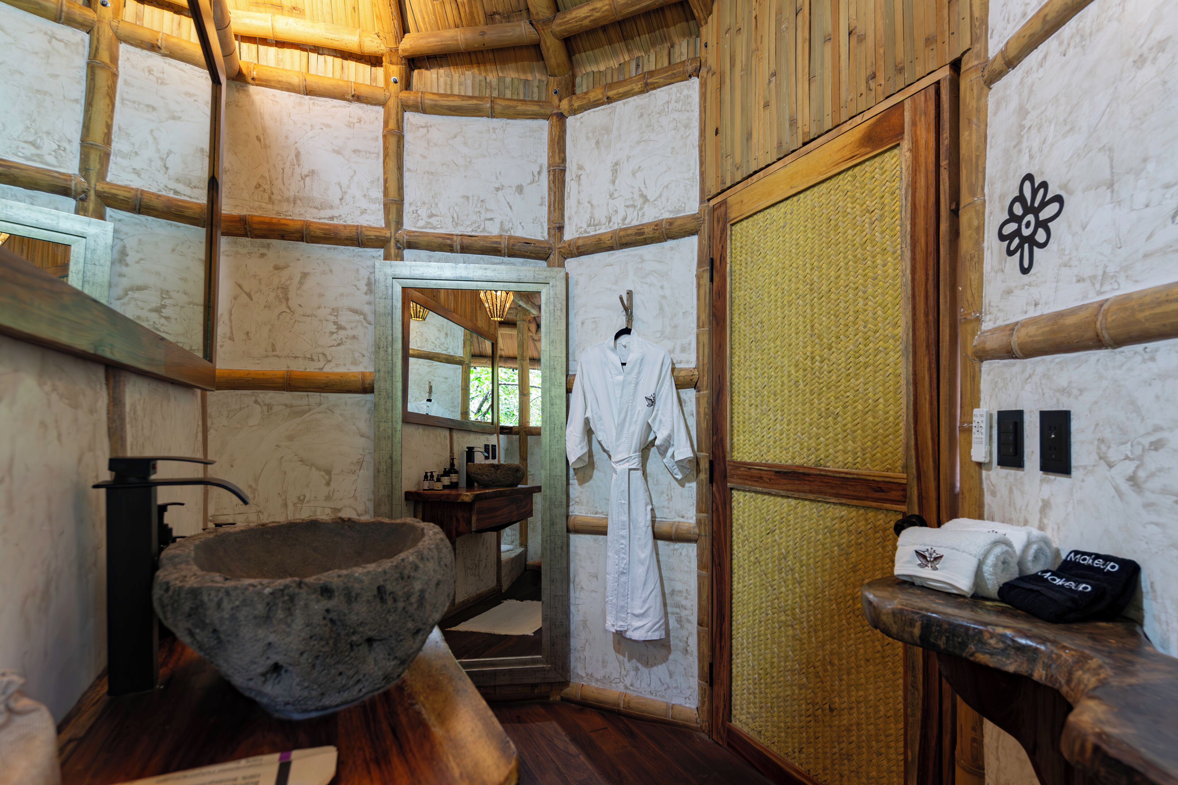 A traditional Japanese-style bathroom with a stone basin, wooden beams, and a sliding door.