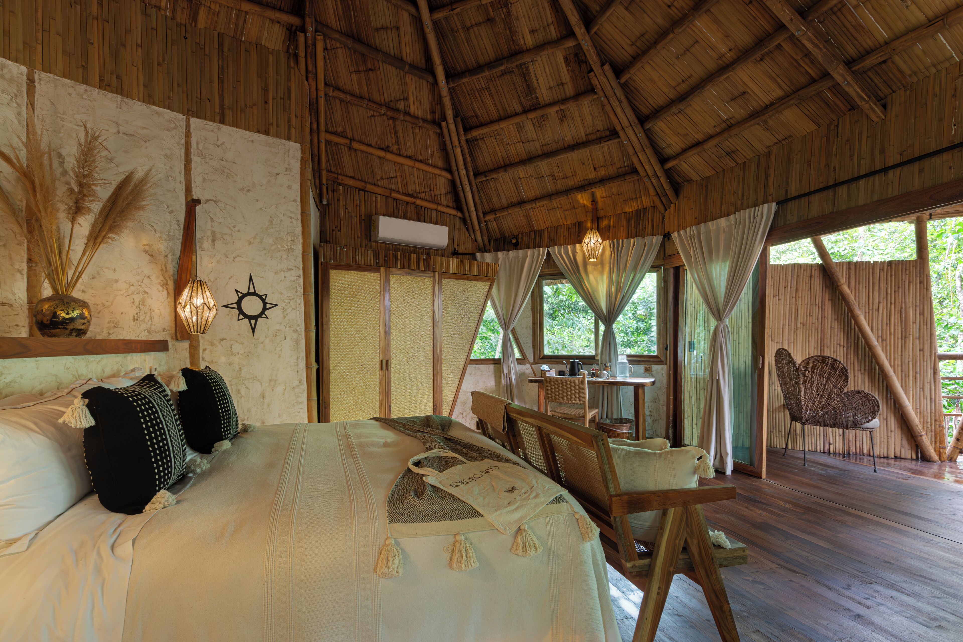 A room with a bed, a table, chairs, and a hanging light fixture.