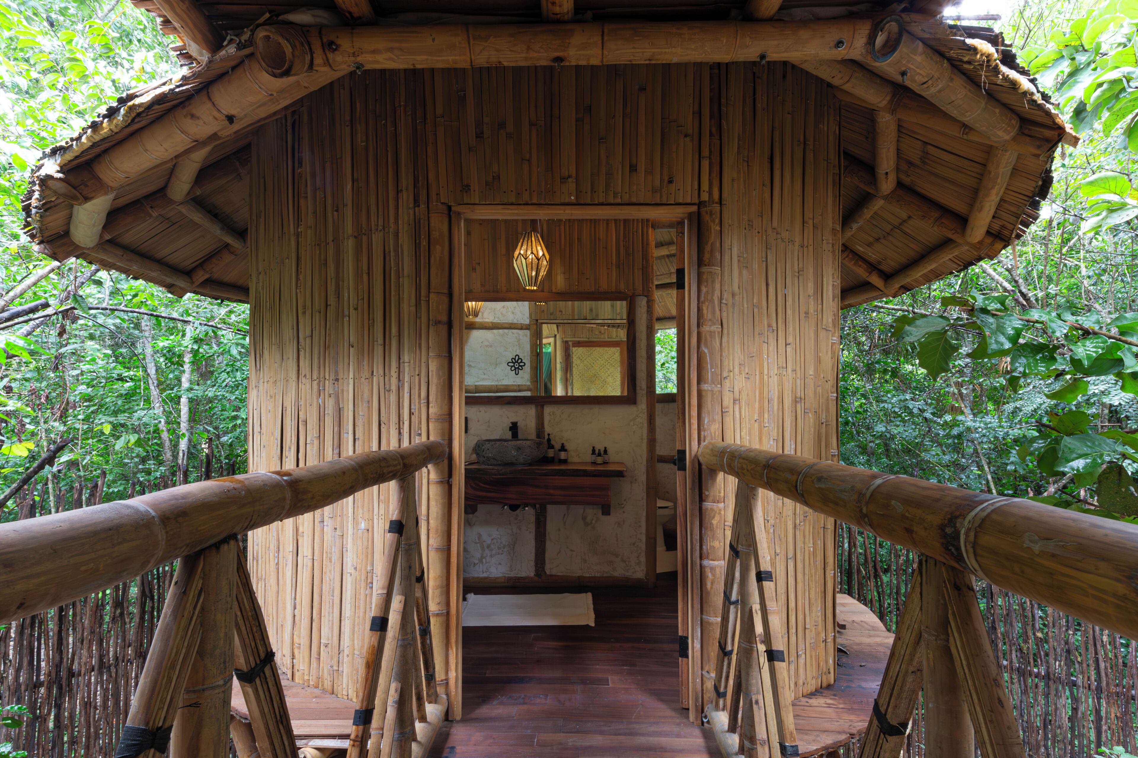 Une structure en bois avec un toit de chaume, une poutre centrale en bois et un luminaire suspendu.