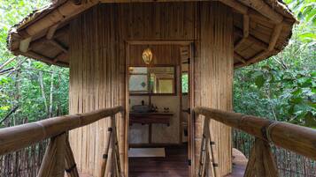 Une structure en bois avec un toit de chaume, une poutre centrale en bois et un luminaire suspendu.