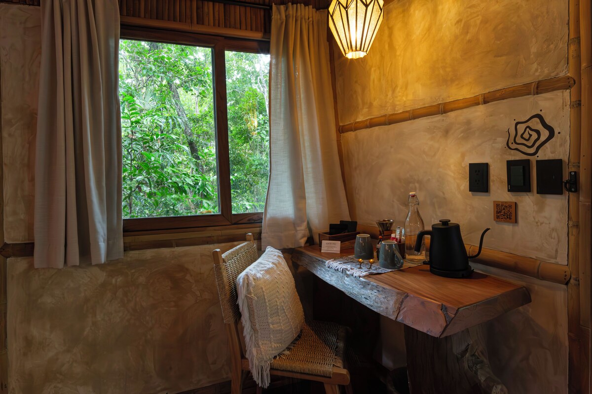 A rustic wooden table with a woven chair, a window with curtains, and a wall-mounted light fixture.