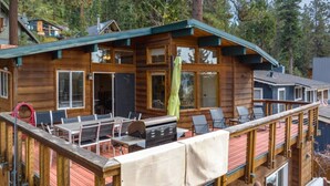 Eine Holzhütte mit Terrasse, Sitzgelegenheit im Freien und Grill.
