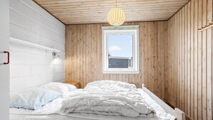 A bedroom with a wooden ceiling, a window, a bed with white bedding, and a bedside lamp. - Beautiful home in Thisted (Thisted)