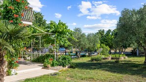 A garden with a pergola, various plants, and a paved walkway. - Cozy apartment in Lozovac with swimming pool (Lozovac)