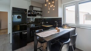 A modern kitchen with a central island, black countertops, and a window providing natural light. - 1 bedroom lovely apartment in Zbandaj (Zbandaj)