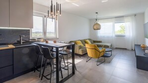 A modern kitchen with a marble countertop and a dining area with bar stools. - 1 bedroom lovely apartment in Zbandaj (Zbandaj)