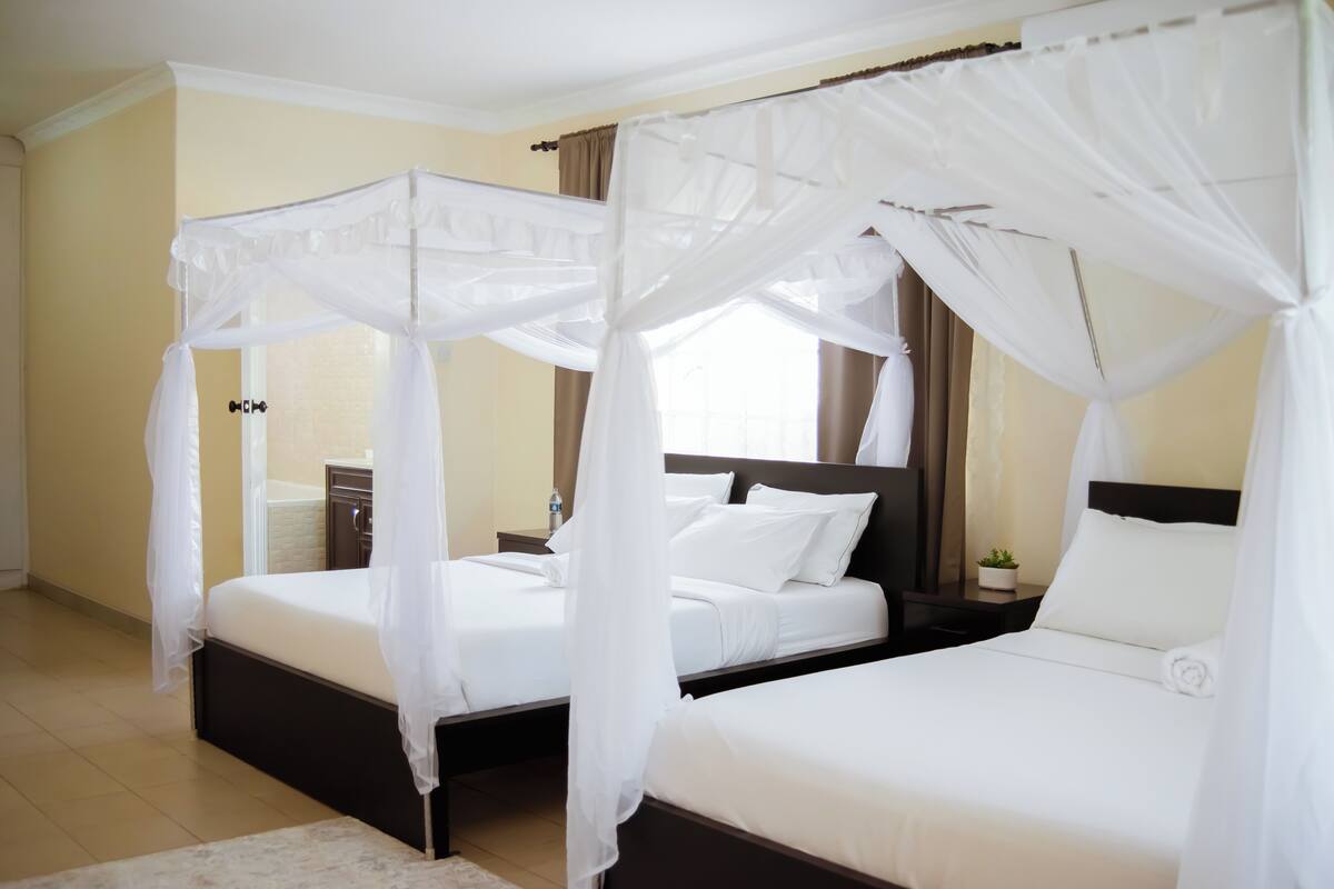 Quarto de hotel com duas camas, cada uma com dossel.