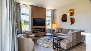 A modern living room with a fireplace, a flat-screen TV, and a sofa. - 2 bedroom amazing home in Voorthuizen (Voorthuizen)