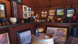 A bar area with wooden barrels, framed artwork, and various decorative items.