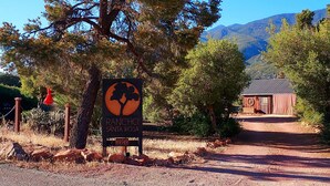 A sign for Rancho Santa Rosa with a tree silhouette, a rustic building, and a clear sky.