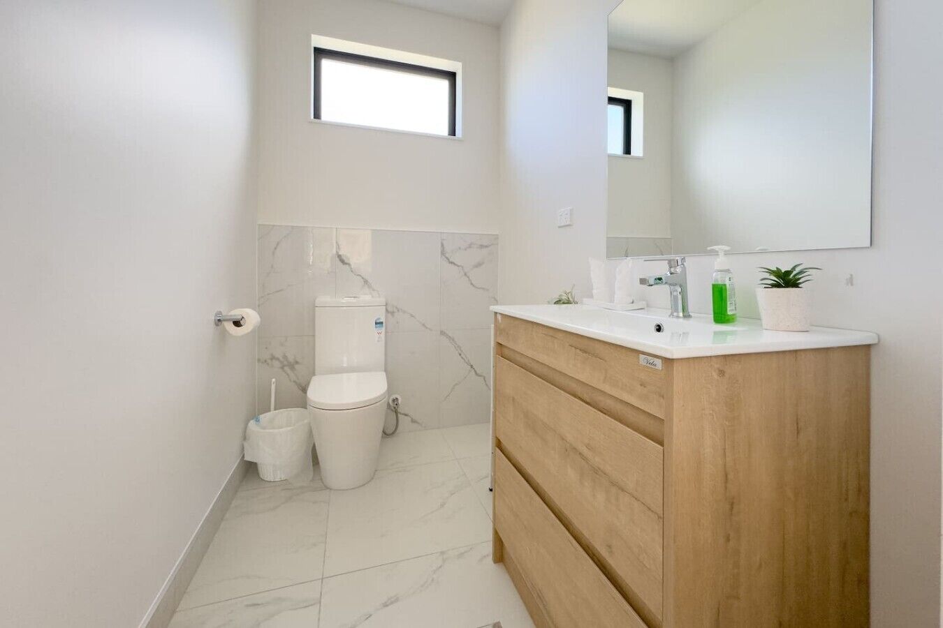 Un bagno moderno con servizi igienici, bidet e mobile contenitore in legno con specchio.