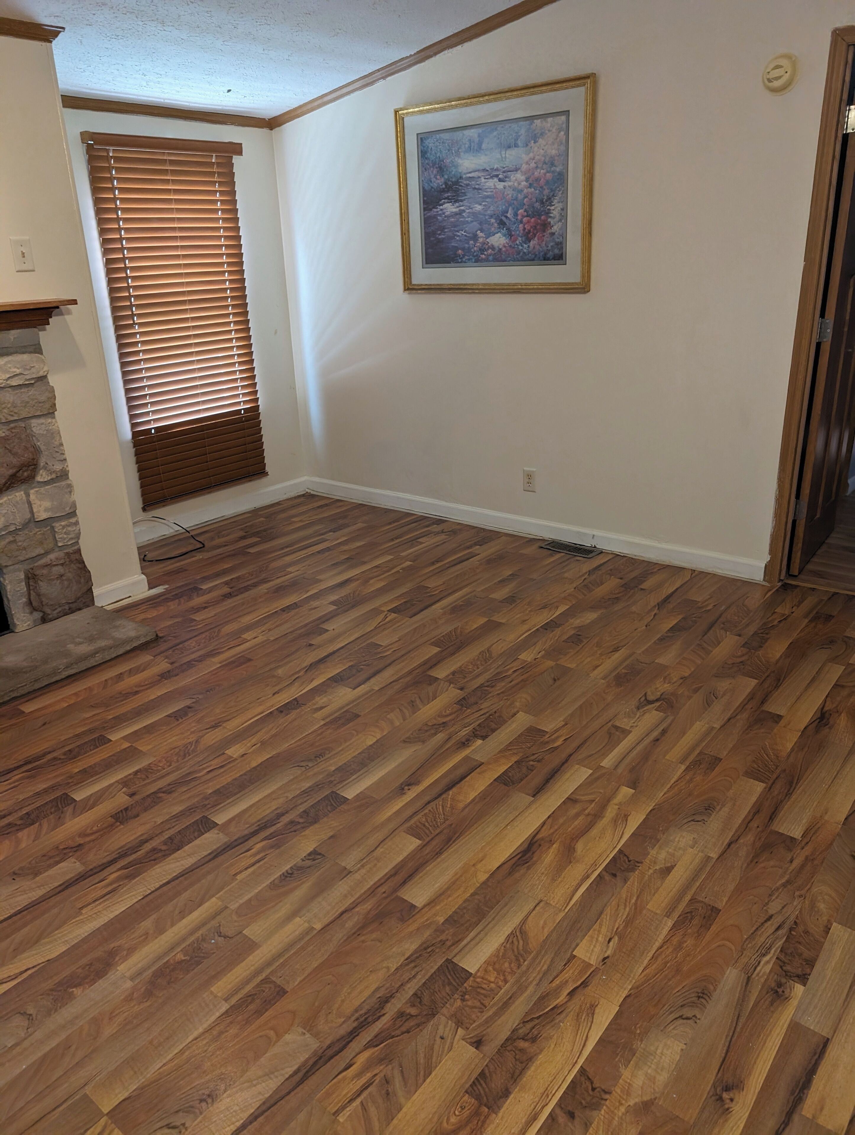 Ein Zimmer mit Holzboden, einer Wand aus Naturstein, einem Gemälde und einer Tür.