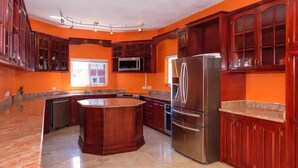 A kitchen with a central island, stainless steel appliances, and dark wooden cabinets.