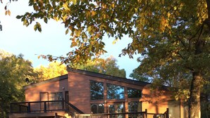 A two-story wooden cabin with a balcony and a staircase leading to the upper level. - Spacious Secluded Lakehouse  (Lindstrom)
