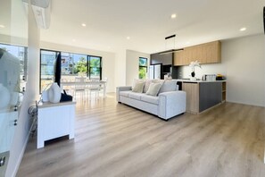 A spacious living area with a sofa, a dining table, and a kitchen area with wooden cabinets.