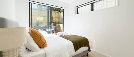 A bedroom with a bed, a window, and a bedside table.