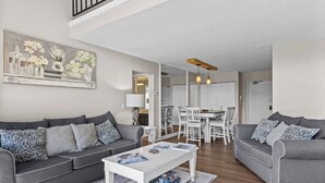 A modern living room with two grey sofas, a white coffee table, and a dining area with white chairs and a wooden table. - Traverse city/Golf/Hiking/Equestrian/Lake  (Williamsburg)