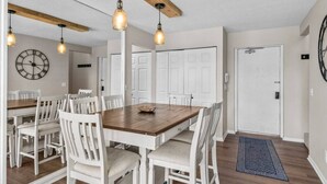 A dining area with a wooden table, white chairs, pendant lights, and a clock on the wall. - Traverse city/Golf/Hiking/Equestrian/Lake  (Williamsburg)