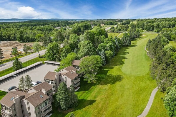 Un quartier résidentiel comprenant un terrain de golf, un parking et un immeuble à plusieurs étages doté de balcons.