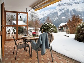 Une terrasse avec une table dressée pour le dîner, offrant une vue sur un paysage montagneux enneigé.