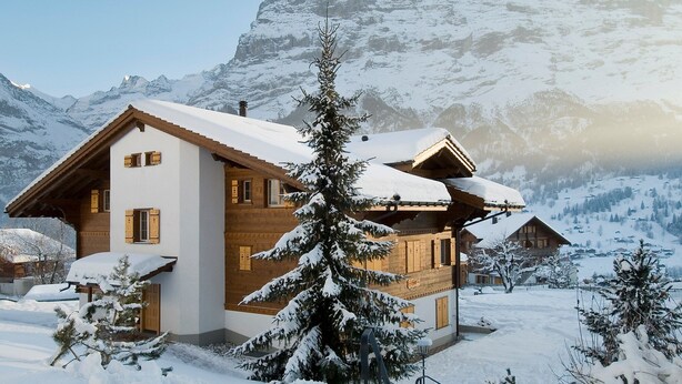 Ein Chalet mit geneigtem Dach, Holzfassade und verschneiter Umgebung.