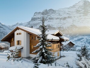 Un bâtiment de style chalet, doté d’un toit en pente, d’une façade en bois et entouré d’un paysage enneigé.