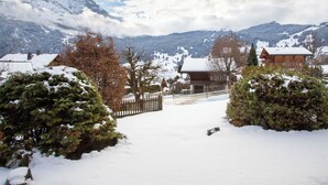 Eine verschneite Berglandschaft mit Holzhütten und einem Holzzaun.
