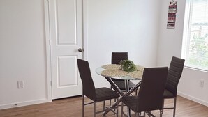 Un coin repas avec une table ronde, quatre chaises et une porte blanche.