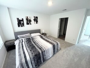 Ein Schlafzimmer mit einem großen Bett, einem Nachttisch und einer Tür zu einem anderen Raum.
