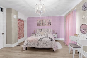 Un dormitorio con cama, tocador, lámpara de araña y reloj de pared.