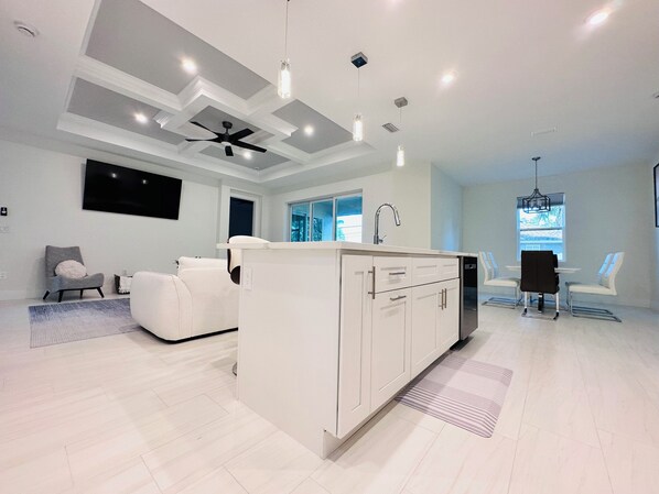 Una cocina moderna con armarios blancos, una isla central y un ventilador de techo.