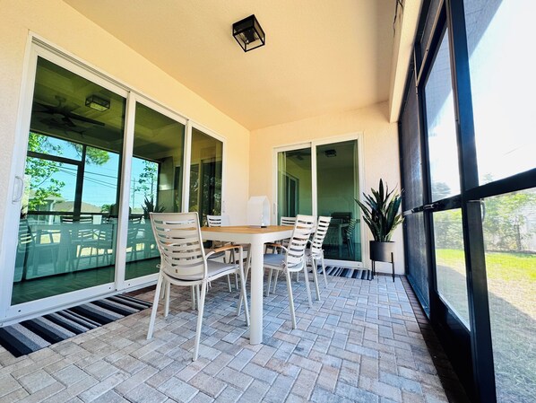 A patio with a table and chairs, large glass doors, and a potted plant.