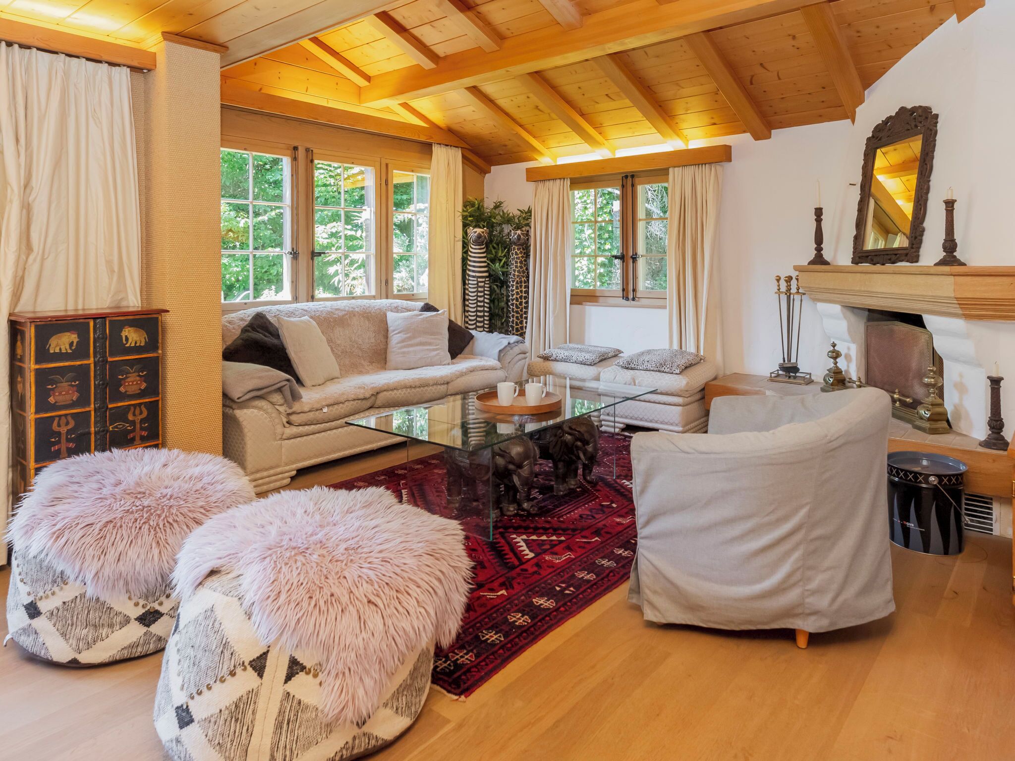 Un salon chaleureux avec un plafond en bois, une cheminée et une grande fenêtre.