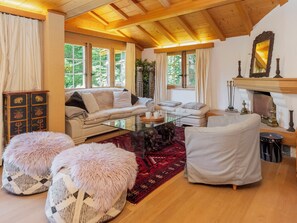 Una sala de estar acogedora con techo de madera, chimenea y un ventanal grande.