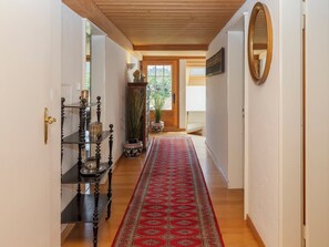 A hallway with a wooden ceiling, a red patterned carpet, and a wooden floor. - Chalet Rebhalde by Interhome (Schönried)
