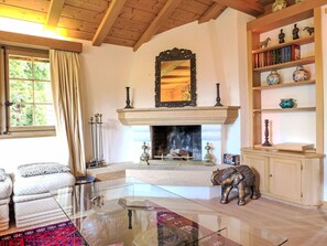 A living room with a fireplace, a glass coffee table, a sofa, a bookshelf, and a decorative elephant statue.