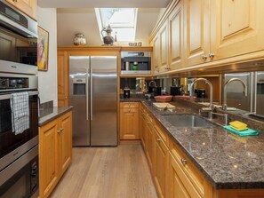 A modern kitchen with stainless steel appliances, wooden cabinets, and a granite countertop. - Chalet Rebhalde by Interhome (Schönried)