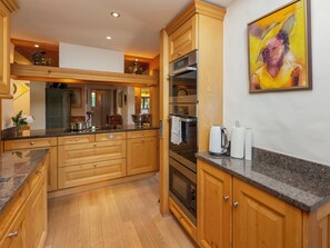 Une cuisine moderne avec des meubles en bois, un plan de travail en granit, des appareils électroménagers en acier inoxydable et un tableau accroché au mur.