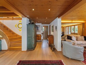 Un interior de madera con una escalera, un armario verde, un sofá y una alfombra estampada.