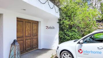 Un bâtiment blanc avec une porte en bois et une enseigne sur laquelle on peut lire « Webbald ». Une voiture blanche, portant le logo « interhome », est garée devant.