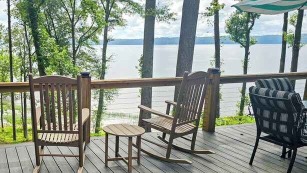 Une terrasse en bois avec une table et des chaises donnant sur un lac.