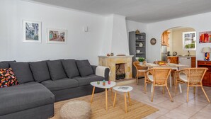 Una sala de estar moderna con un sofá gris, una chimenea y un comedor con sillas de mimbre.