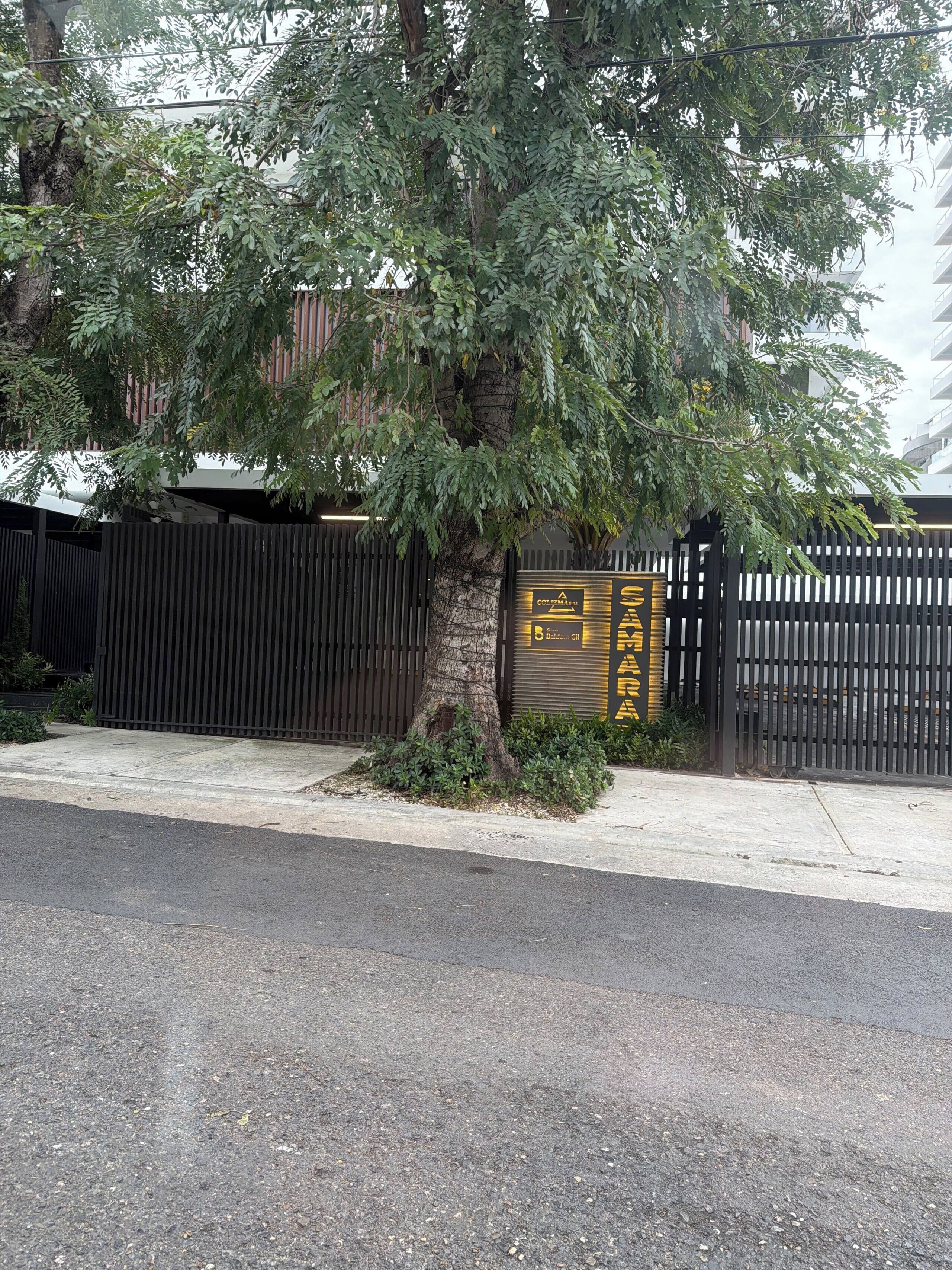 Une propriétéClose, avec un arbre, une clôture et un bâtiment en arrière-plan.